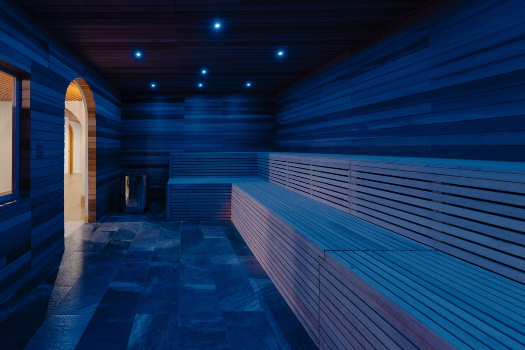 Dimly lit wooden sauna room with tiered benches and small blue ceiling lights